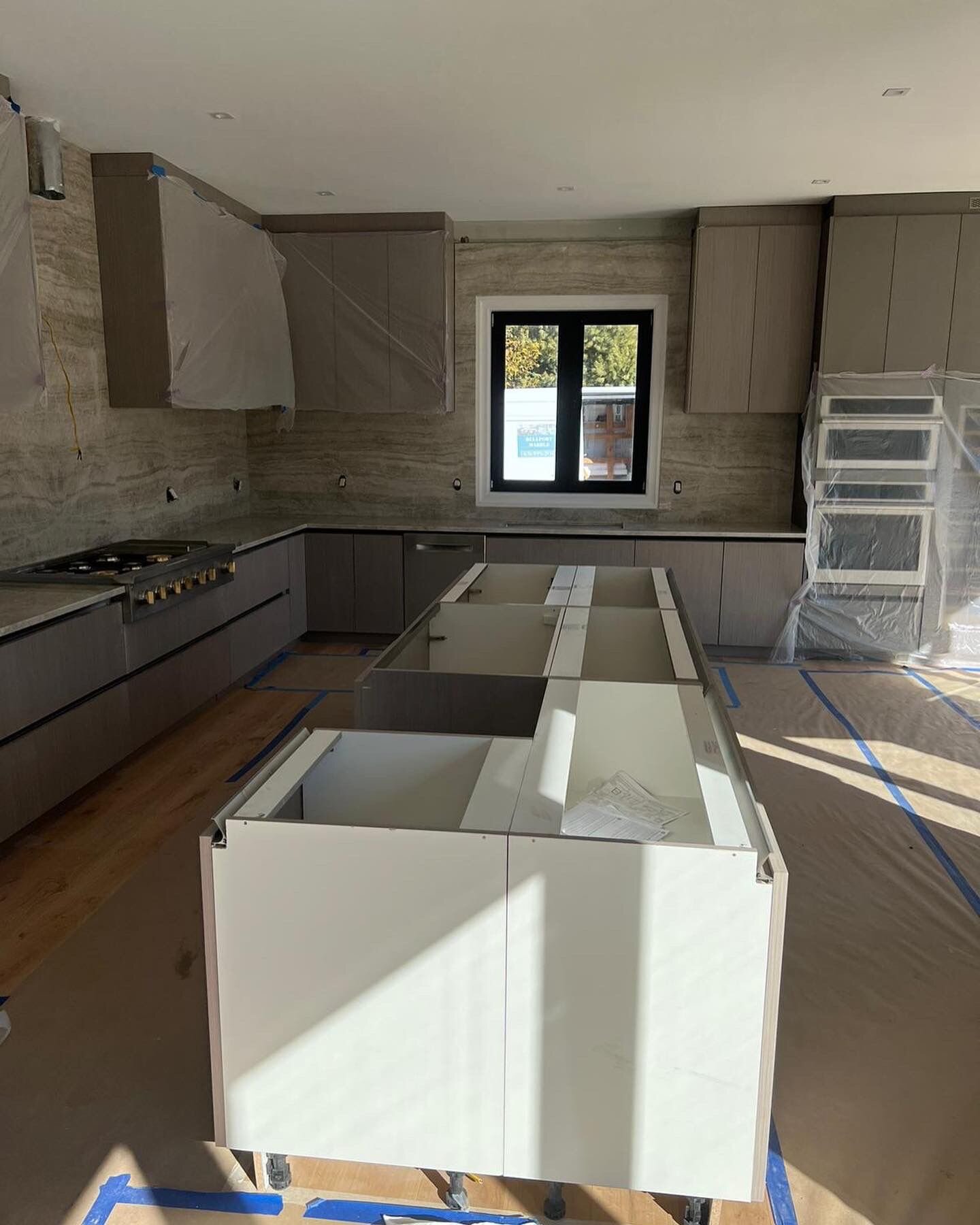 Full kitchen cabinetry installation with taupe shaker cabinets and stone backsplash