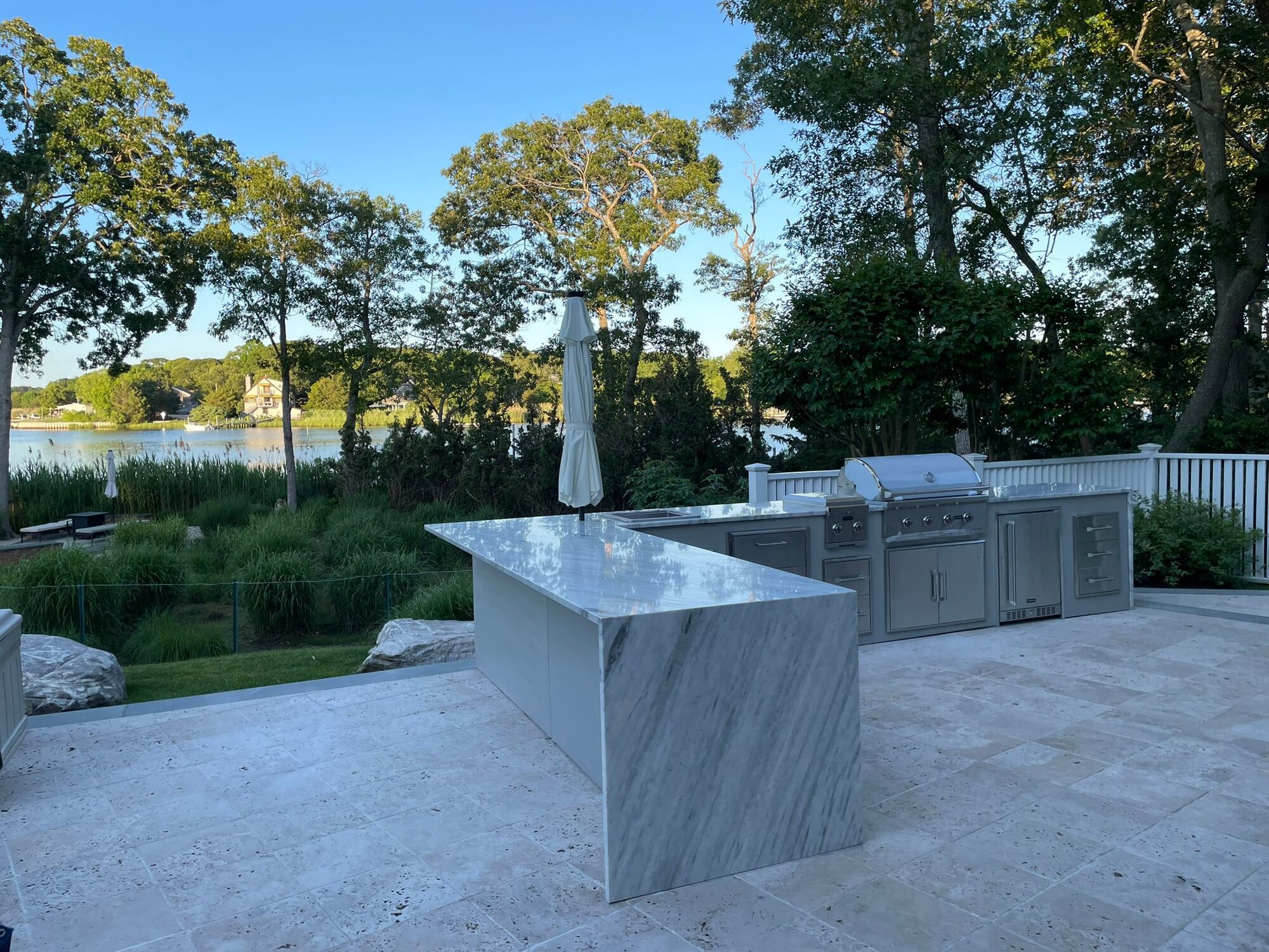 Exquisite outdoor kitchen with marble waterfall island overlooking the water