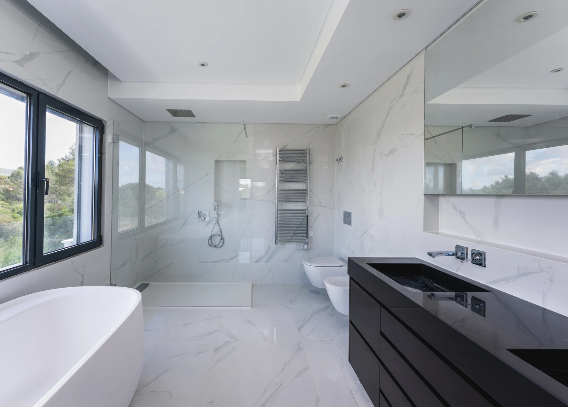 Black vanity beside glass shower and window